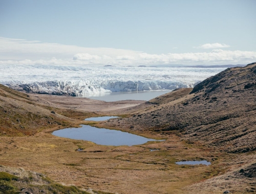 A mountainous landscape in Greenland, encircling an oval lake that sits at the center