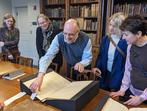 Several people gathered around an Arctic manuscript