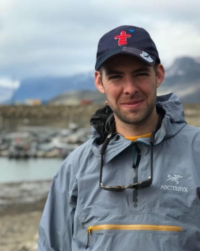 An image of Hunter Snyder in front of a mountain landscape, foregrounded by a bay.