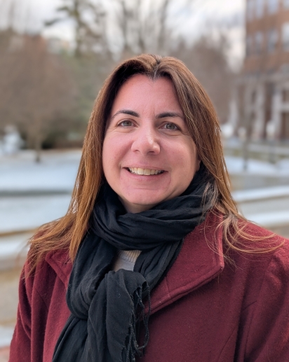 A photo of a smiling woman, Dr. Kathy Mary E. Snow, wearing a dark red coat and a black scarf against a wintry background.