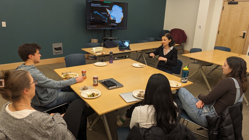 Students discuss climate modelling around a table with scientist Dr. Helene Seroussi