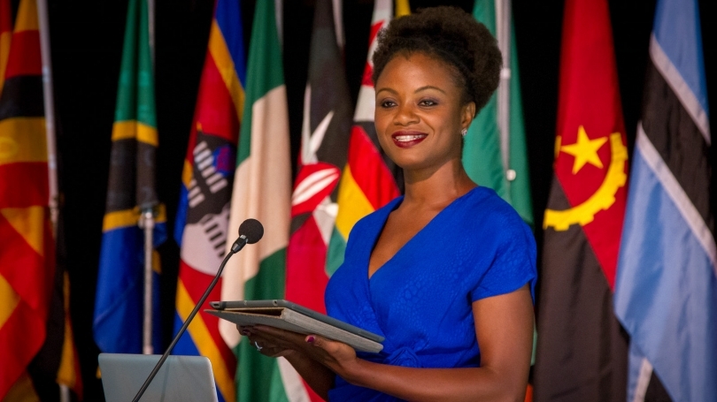 Patrice Juah stands on stage at a podium.